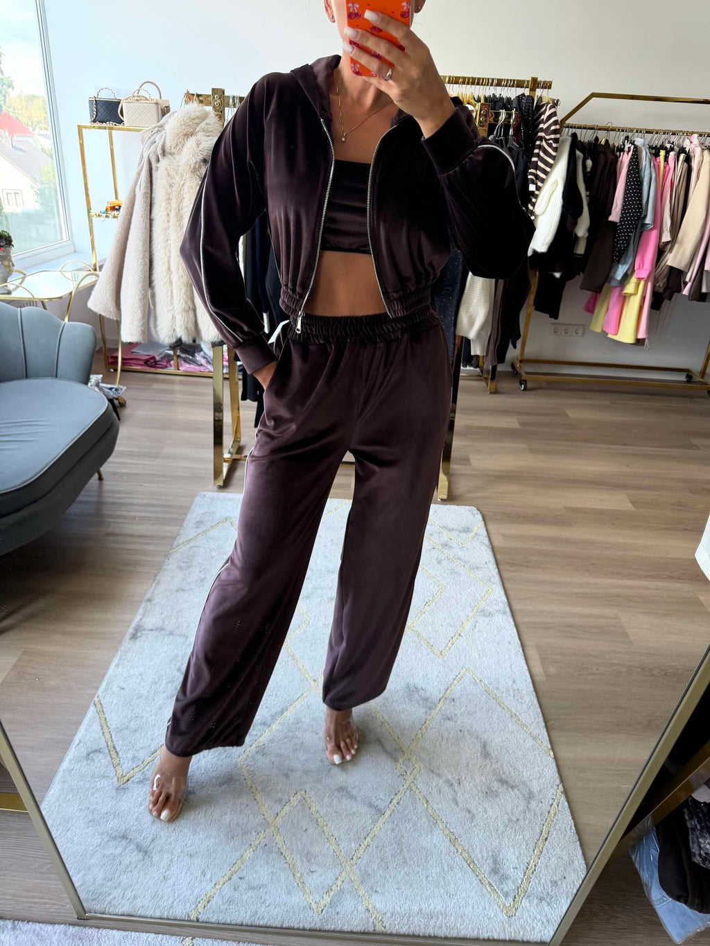 Tamsiai rudas veliūrinis moteriškas laisvalaikio kostiumas su gobtuvu, trumpintu džemperiu su užtrauktuku ir tiesaus kirpimo kelnėmis.